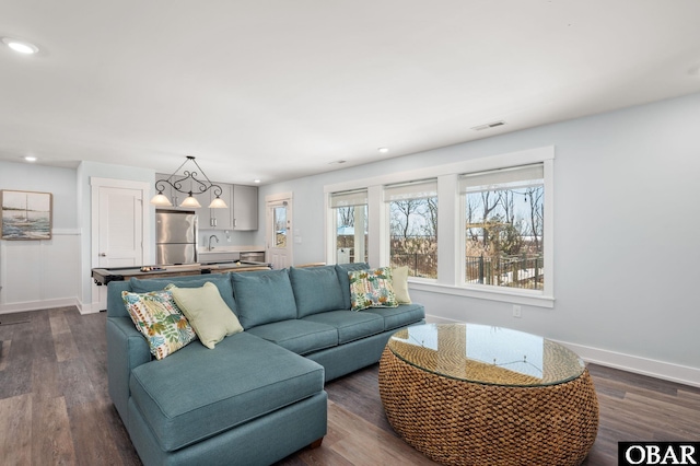 living area with baseboards, visible vents, dark wood-type flooring, and recessed lighting