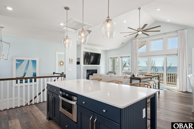 kitchen with light countertops, dark wood-type flooring, a glass covered fireplace, and stainless steel oven