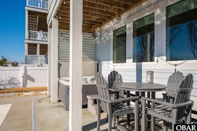 view of patio with outdoor dining space, fence, and a hot tub