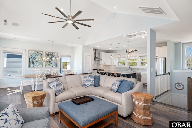 living room featuring dark wood-type flooring, a chandelier, visible vents, and high vaulted ceiling