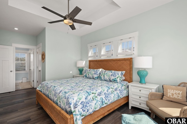 bedroom with dark wood-type flooring, a raised ceiling, a ceiling fan, and recessed lighting