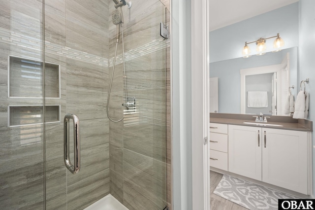 full bathroom featuring a stall shower, wood finished floors, and vanity