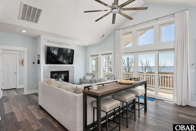 living area featuring a fireplace, visible vents, dark wood finished floors, and a wealth of natural light