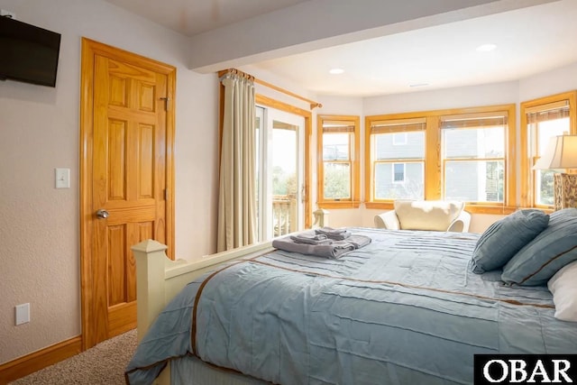 bedroom featuring access to exterior, a textured wall, and baseboards