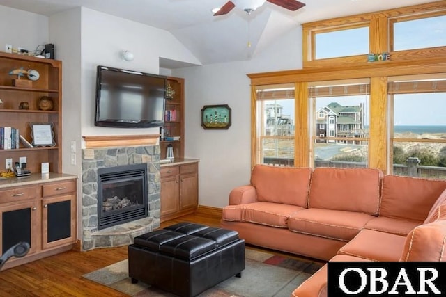 living room with wood finished floors, ceiling fan, a fireplace, and vaulted ceiling