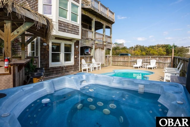 view of swimming pool with a patio, fence, and a hot tub