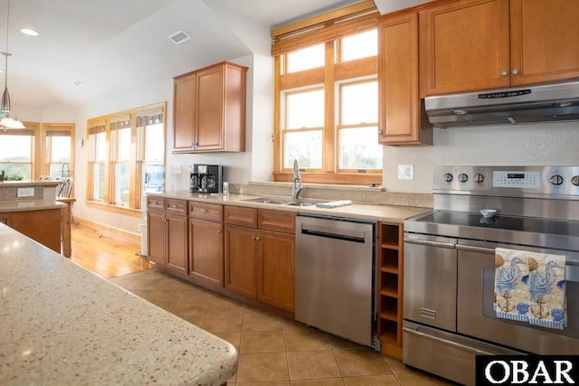 kitchen with visible vents, under cabinet range hood, light stone counters, appliances with stainless steel finishes, and a sink