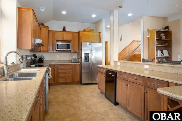 kitchen featuring a sink, under cabinet range hood, appliances with stainless steel finishes, brown cabinetry, and light stone countertops