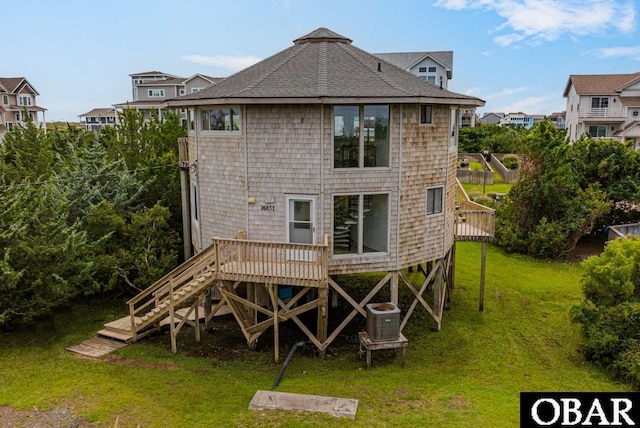 back of property with roof with shingles, a wooden deck, cooling unit, and a yard