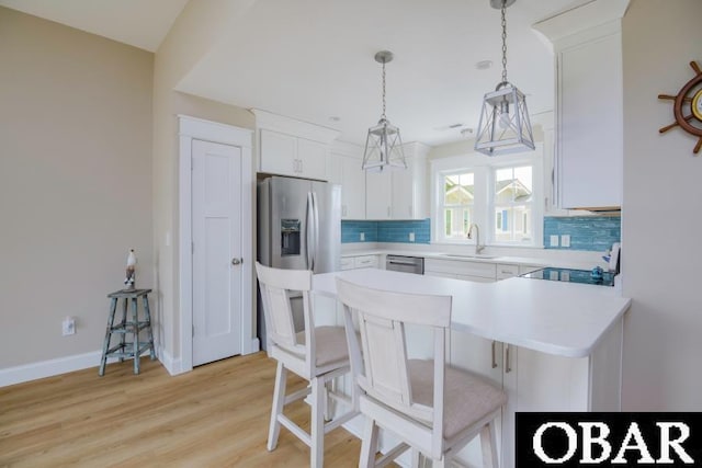 105D Colington Pointe Cir Unit 104-D, Kill Devil Hills, NC 27948 - kitchen with light countertops, backsplash, stainless steel appliances, white cabinetry, and a peninsula