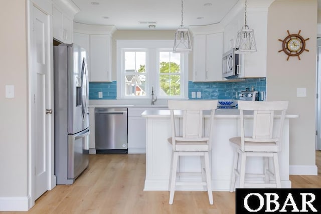 105D Colington Pointe Cir Unit 104-D, Kill Devil Hills, NC 27948 - kitchen featuring stainless steel appliances, tasteful backsplash, light wood-type flooring, and a kitchen breakfast bar