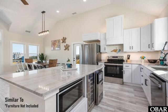 kitchen with appliances with stainless steel finishes, a kitchen island, visible vents, and light stone countertops