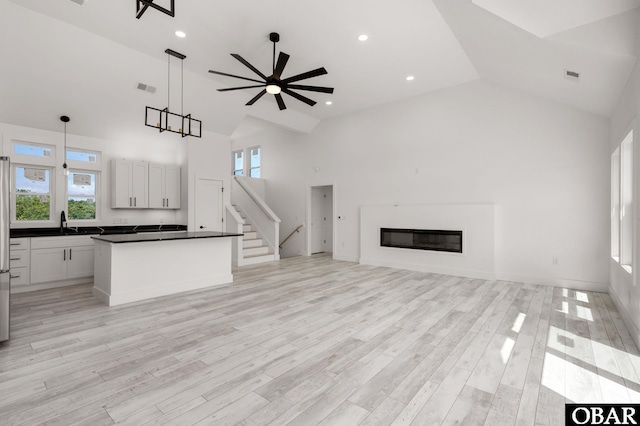 2002 Sandpiper Rd Lot 12, Corolla, NC 27927 - unfurnished living room featuring high vaulted ceiling, a glass covered fireplace, ceiling fan, light wood-type flooring, and recessed lighting