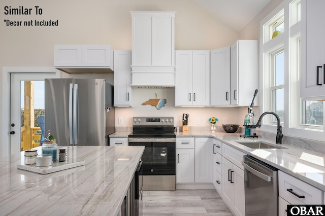 kitchen with white cabinets, light stone countertops, stainless steel appliances, and a sink