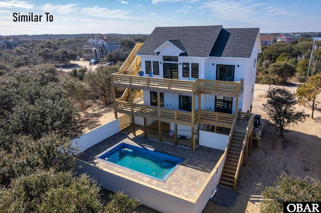 rear view of property featuring roof with shingles, a patio area, a balcony, and a hot tub