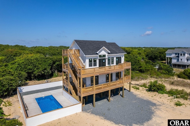 2002 Sandpiper Rd Lot 12, Corolla, NC 27927 - rear view of house featuring a view of trees, a deck, an outdoor pool, and a balcony