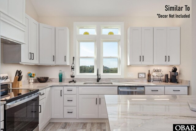 kitchen with light stone counters, stainless steel appliances, a sink, white cabinetry, and custom exhaust hood