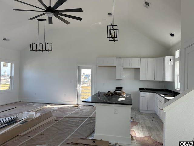 kitchen featuring dark countertops, a kitchen island, visible vents, and white cabinets