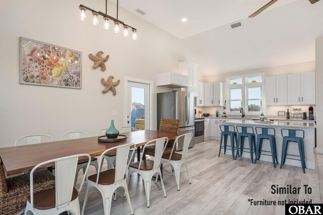 dining space featuring high vaulted ceiling, light wood-style flooring, visible vents, and recessed lighting