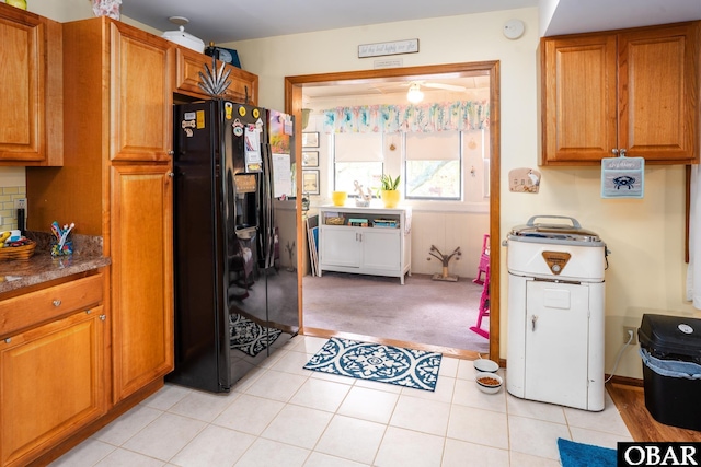kitchen featuring light tile patterned floors, brown cabinetry, black fridge with ice dispenser, and light colored carpet
