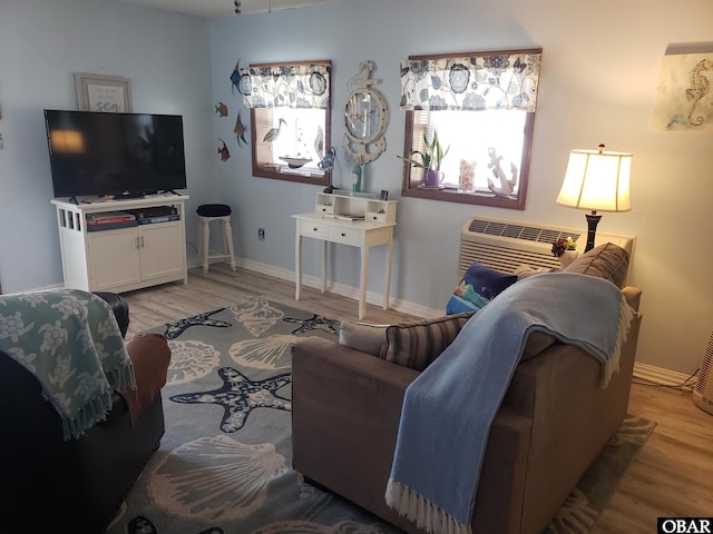 living room with an AC wall unit, light wood finished floors, and baseboards