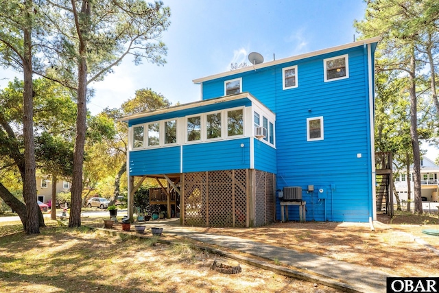 rear view of house with a sunroom, stairway, cooling unit, a carport, and driveway
