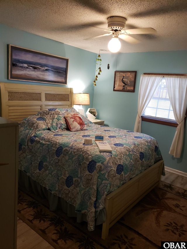 bedroom with a textured ceiling, ceiling fan, and wood finished floors