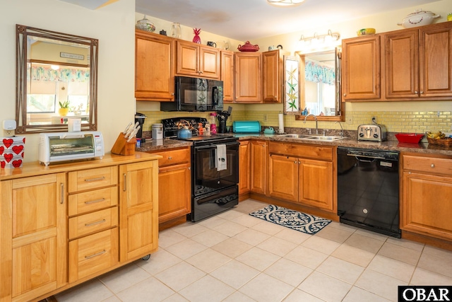 kitchen with decorative backsplash, dark countertops, a sink, light tile patterned floors, and black appliances