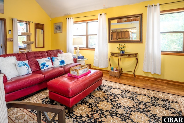 living area with baseboards, vaulted ceiling, and wood finished floors