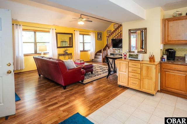 living area with stairs, ceiling fan, lofted ceiling, and light wood-type flooring