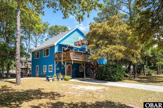beach home with stairway, a front yard, and a deck