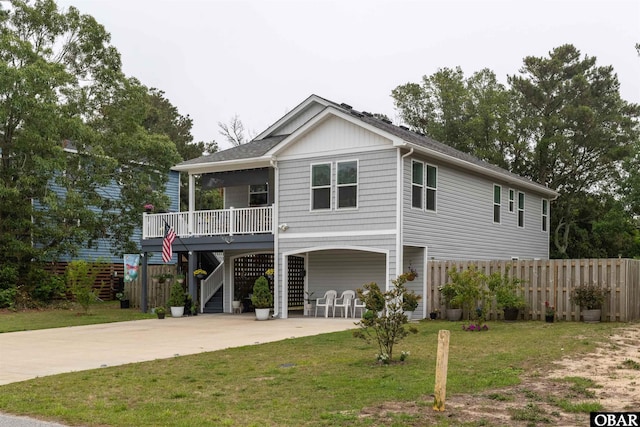 raised beach house featuring fence, driveway, stairway, a carport, and a front yard