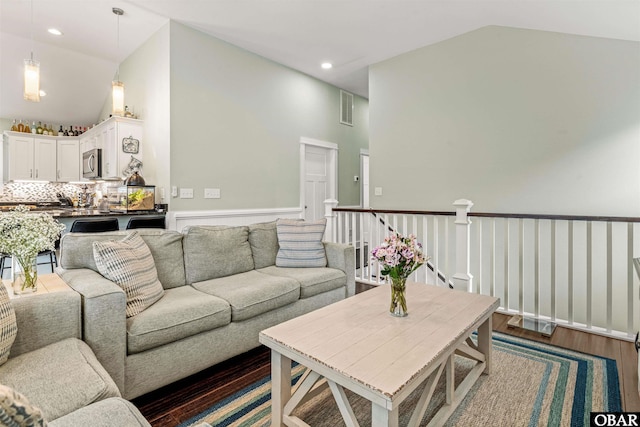 living room featuring dark wood-type flooring, recessed lighting, visible vents, and high vaulted ceiling