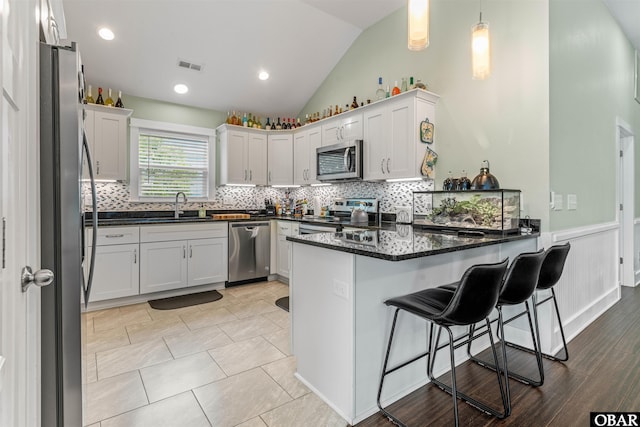 kitchen featuring decorative light fixtures, visible vents, appliances with stainless steel finishes, a sink, and a peninsula