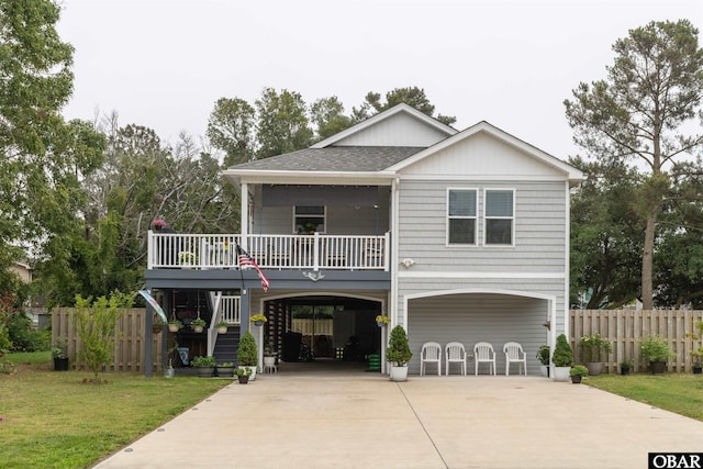 beach home with driveway, stairway, roof with shingles, a front lawn, and a carport