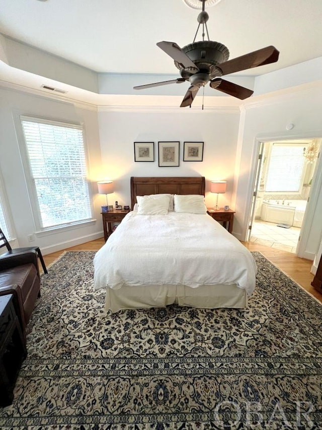 bedroom with multiple windows, visible vents, wood finished floors, and ornamental molding