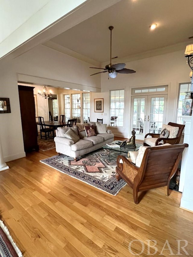 living area featuring light wood-style floors, french doors, a high ceiling, and ceiling fan with notable chandelier