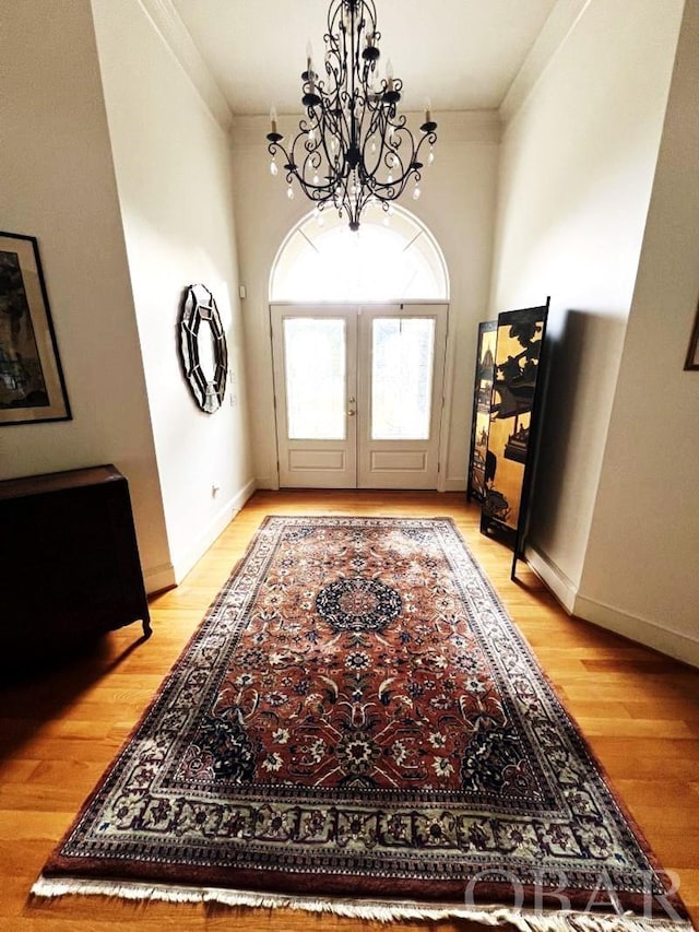 entryway with french doors, a notable chandelier, light wood-style flooring, and baseboards