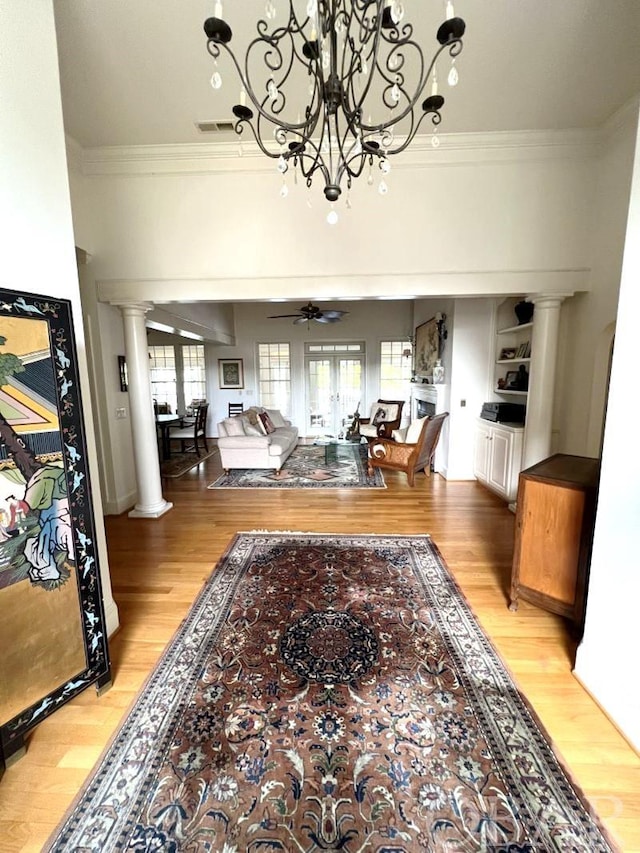 living room with light wood-style floors, decorative columns, a ceiling fan, and crown molding