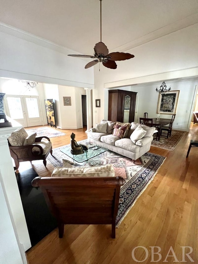 living room with a ceiling fan, decorative columns, light wood-style flooring, and crown molding