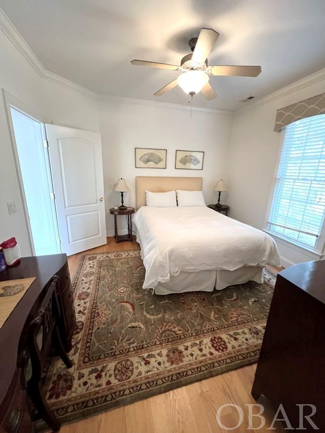 bedroom with ceiling fan, ornamental molding, wood finished floors, and visible vents