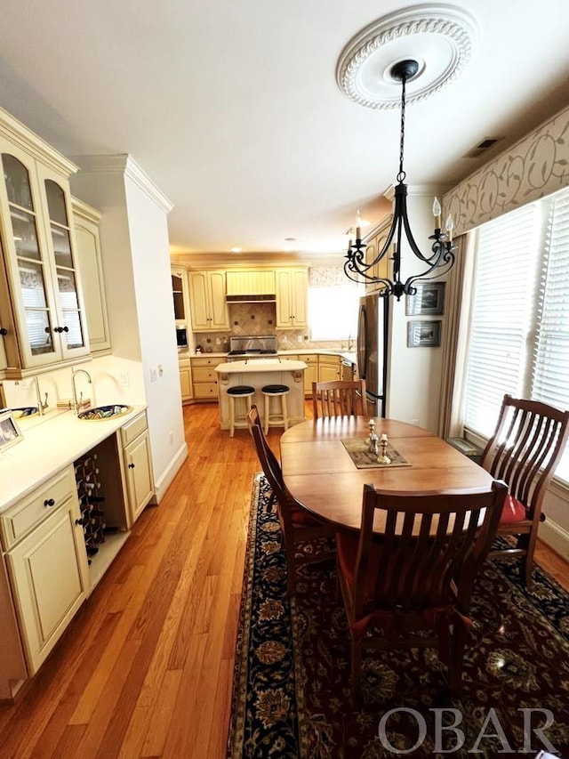 dining space featuring light wood-type flooring, baseboards, visible vents, and a notable chandelier