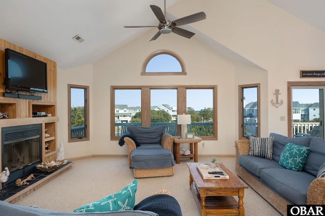 carpeted living room with ceiling fan, high vaulted ceiling, a large fireplace, visible vents, and baseboards