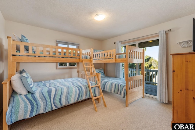 bedroom with a textured ceiling, access to outside, and carpet