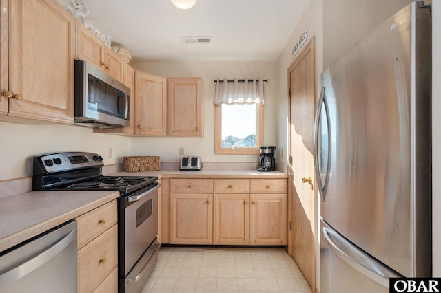 kitchen with light brown cabinets, visible vents, stainless steel appliances, and light countertops