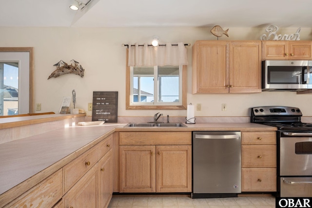 kitchen with light brown cabinets, appliances with stainless steel finishes, light countertops, and a sink