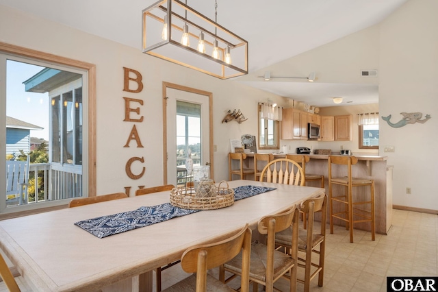 dining room featuring lofted ceiling, a healthy amount of sunlight, visible vents, and light floors