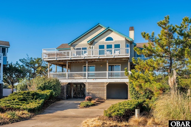 coastal home featuring driveway, a chimney, and a carport