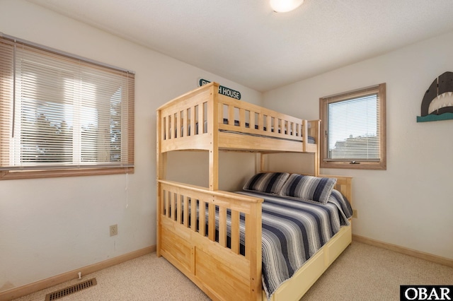 bedroom featuring baseboards, visible vents, and light colored carpet