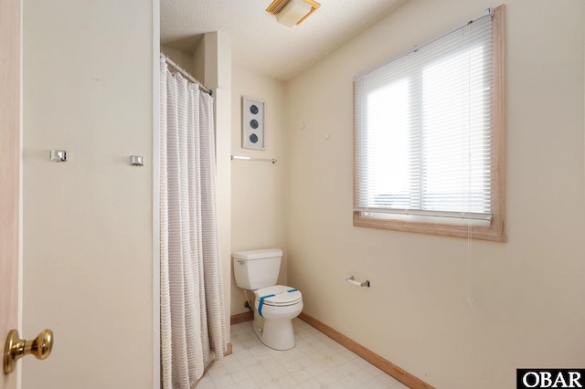 full bathroom with a textured ceiling, toilet, a shower with shower curtain, baseboards, and tile patterned floors